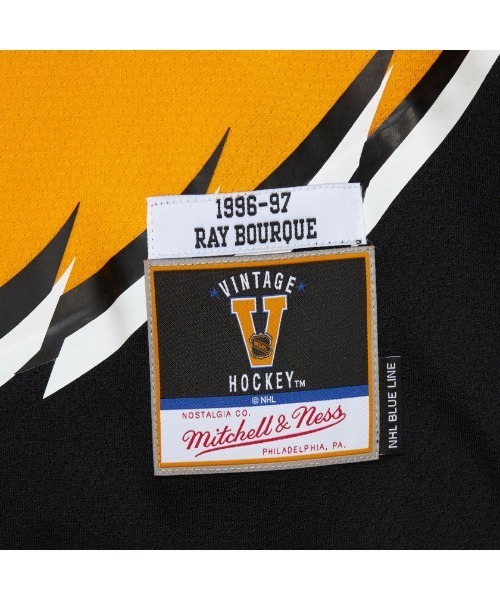 Mitchell&Ness（ミッチェル&ネス）の「Mitchell & Ness Blue Line Ray Bourque Boston Bruins Dark 1996 Jersey（ミッチェルアンドネス ブルー ライン レイ バーク ボストン ブルーインズ ダーク 1996 ジャージ）（Tシャツ/カットソー・メンズ・ゴールド・LARGE/MEDIUM）」の4枚目の写真