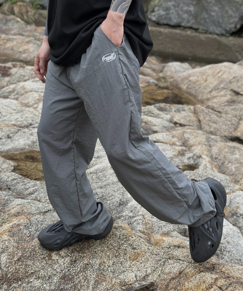 PEACEOFMIND(ピースオブマインド)の「ロゴナイロンワイドトラックパンツ(グレー)(スウェットパンツ・メンズ・その他・MEDIUM/LARGE/X-LARGE)」の1枚目の写真